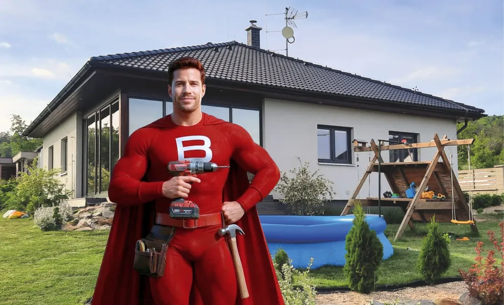 muž s vŕtačkou v ruke, v pozadí dom
